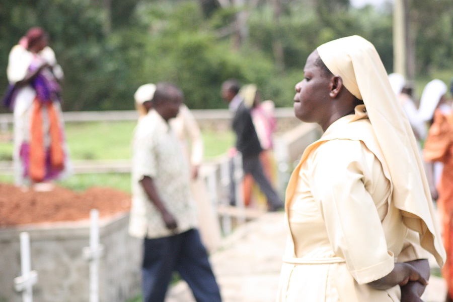 Sr. Goretti, the caretaker of Sr. John Battista, watches prayerfully as the final cement is put over her grave