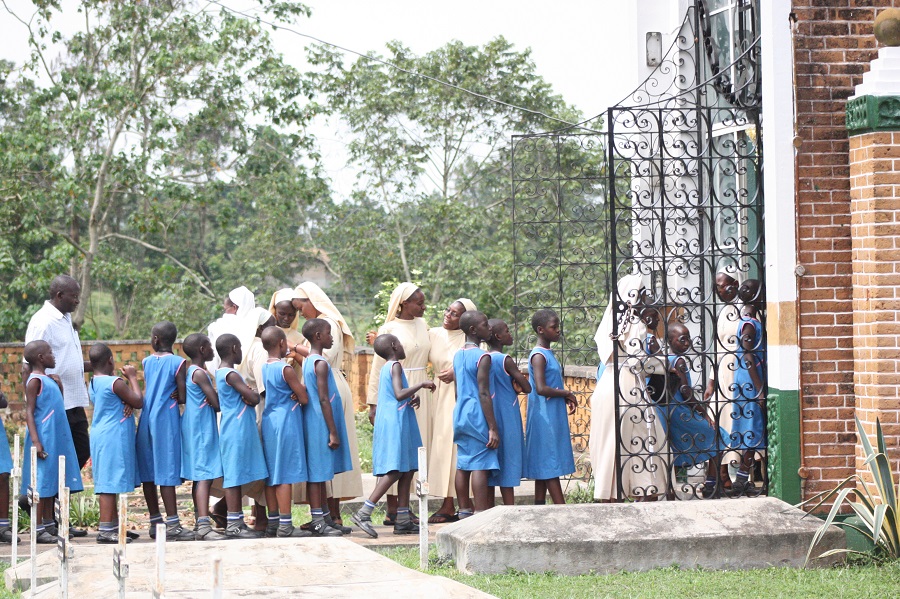 Children from Stella Maris Primary Boarding School, including CARITAS' own Martha Mbejjo, go to Mother Kevin to leave their prayer intentions