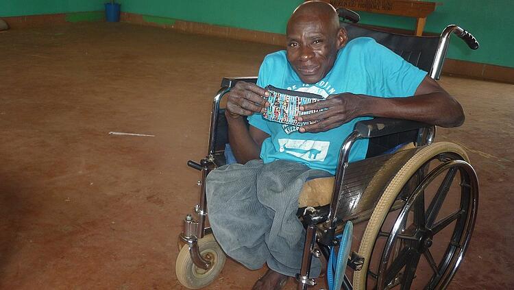 image of a man sitting in a wheelchair holding beaded coin purse image of a man sitting in a wheelchair holding beaded coin purse