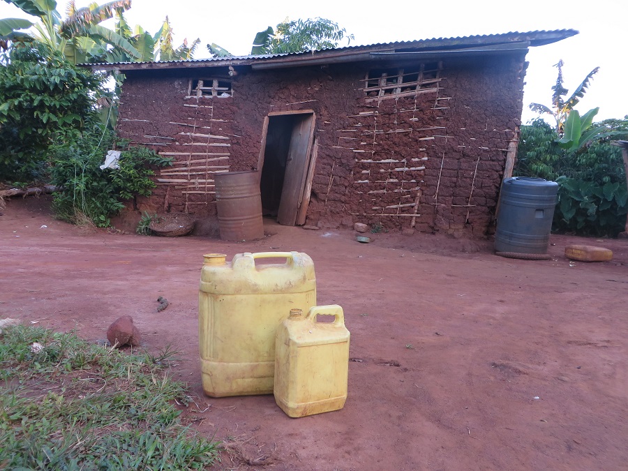 The family's home. The two barrels on either side of the door are used to collect run off from the roof when it rains. The jerry cans in the front are used to haul water when the barrels are empty. The family's home. The two barrels on either side of the door are used to collect run off from the roof when it rains. The jerry cans in the front are used to haul water when the barrels are empty.